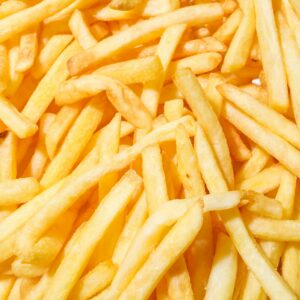 A close-up of delicious crispy French fries with a vibrant yellow background.